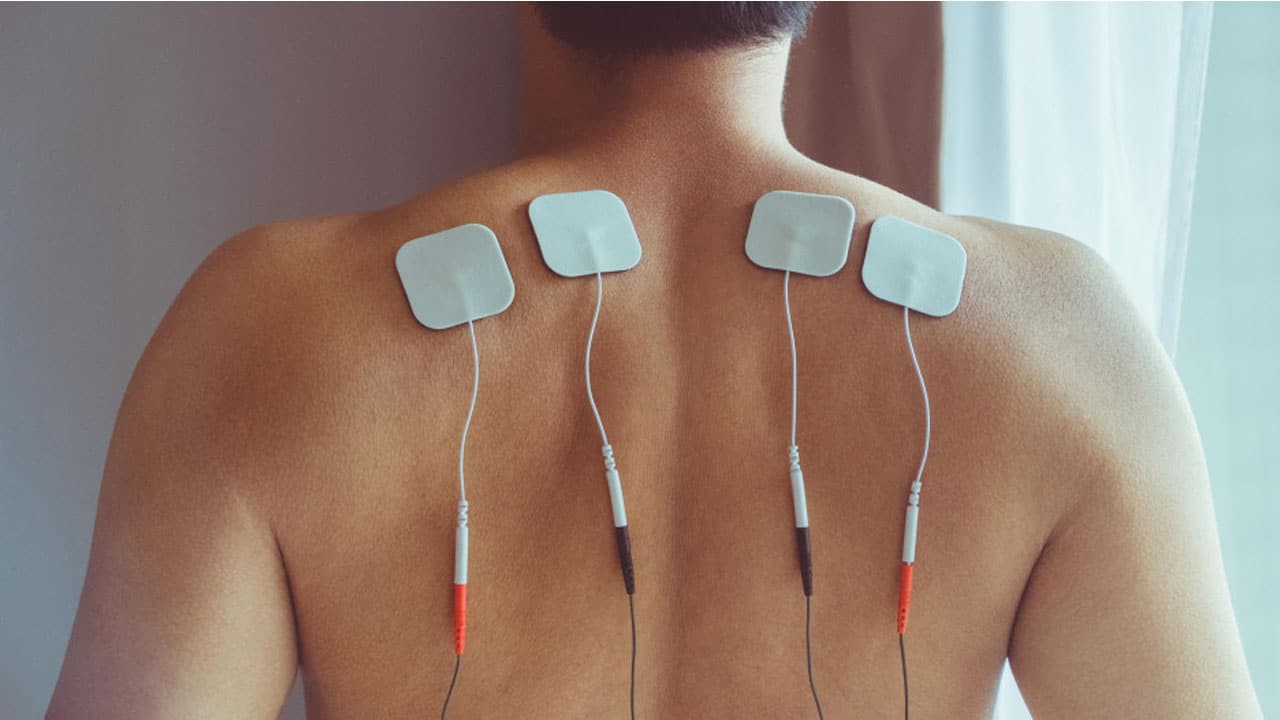 homme de dos portant des capteurs de neurostimulation électrique transcutanée (tens)