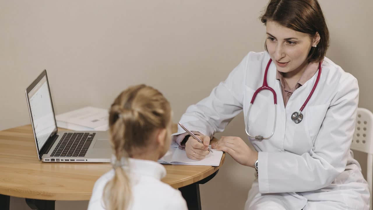 médecin femme souraiante en consultation avec une petite fille