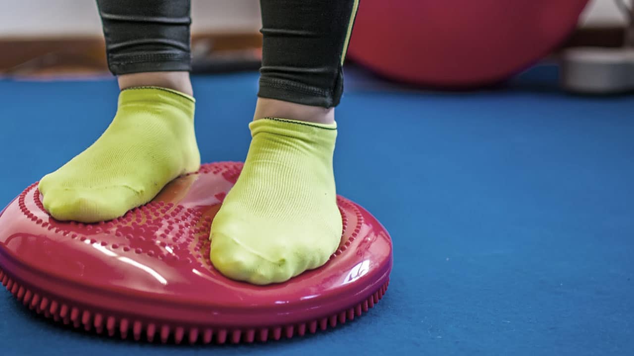 enfant debout sur un coussin de proprioception