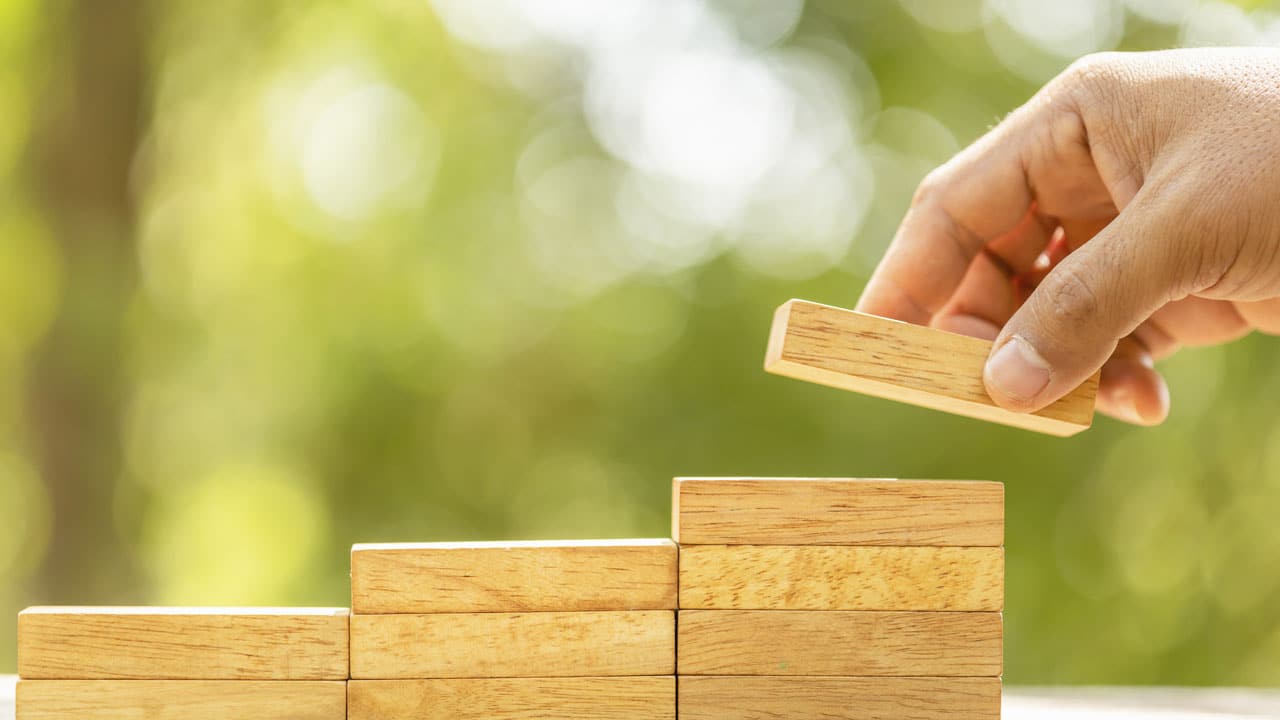 main construisant quelque chose avec des petites briques en bois