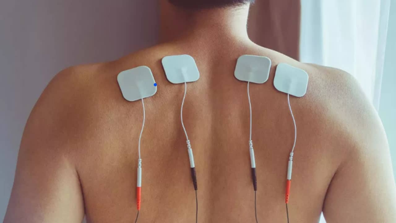 photo du dos d'un homme portant des electrode de stimulateur transcutané (TENS)