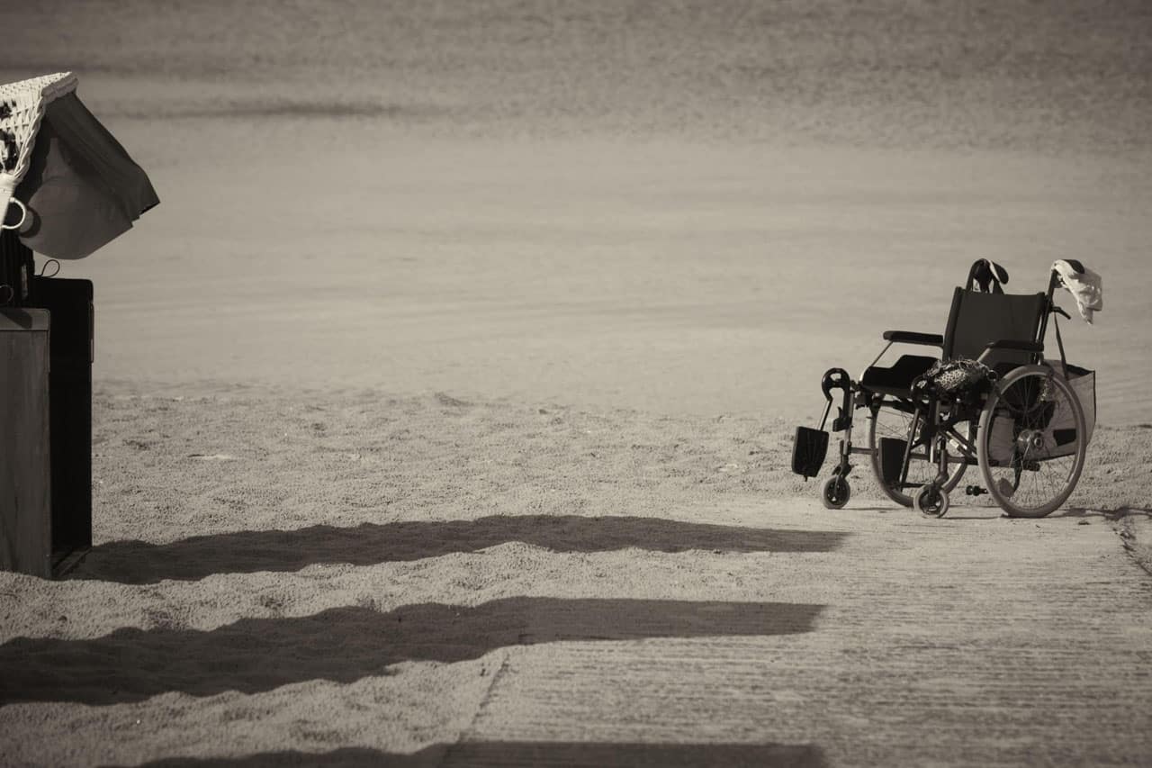 fauteuil roulant devant une cabine de plage sur le sable